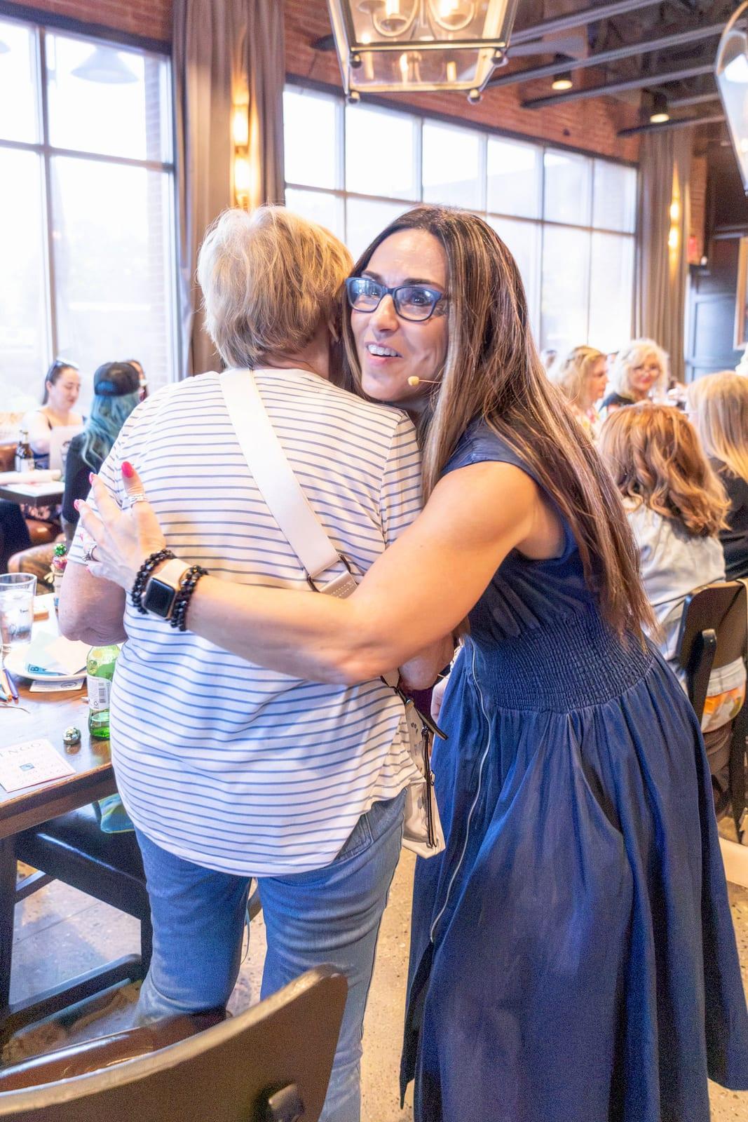 Maggie Sitar hugging a guest at Lucky Ladies
